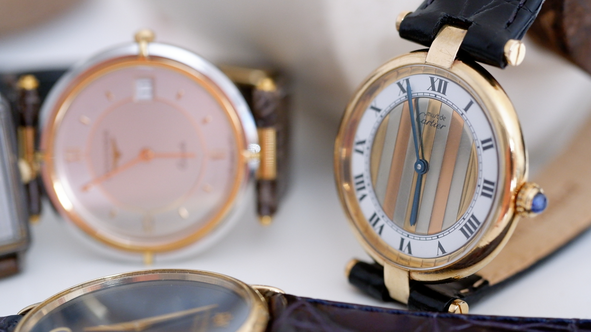Artistic Image of a Cartier Ladies Vintage Watch in Gold with a Longine Ladies Vintage Watch in the Background
